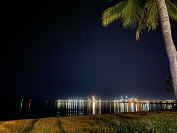 Scenic view of illuminated beach against clear sky at night