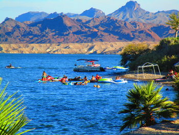 Boats in sea against mountains