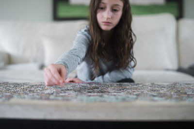 Young girl working on a jigsaw puzzle indoors