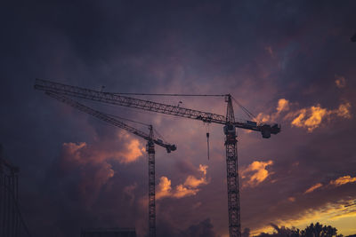 Low angle view of silhouette crane against sky at sunset