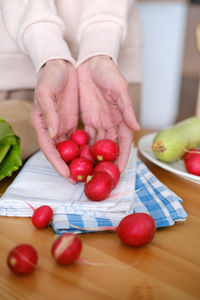 Cropped hand of person holding tomatoes on table