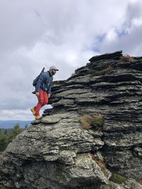 Low angle view of man on rock against sky
