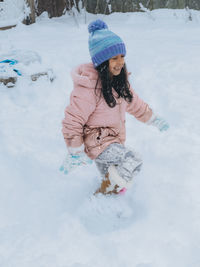 Diverse mixed race pre school toddler girl outdoors in winter playing with snow 