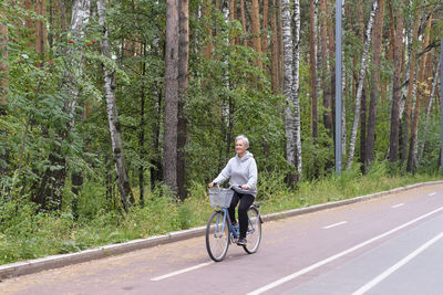 Man riding bicycle on road in forest