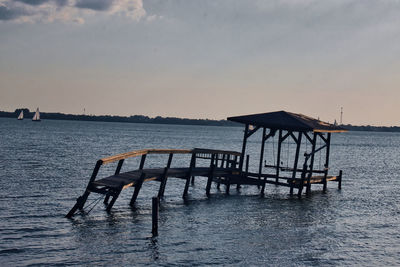 Pier over sea against sky during sunset