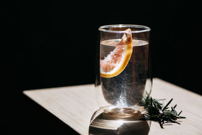 Refreshing cool drink with orange in the sun on a black background