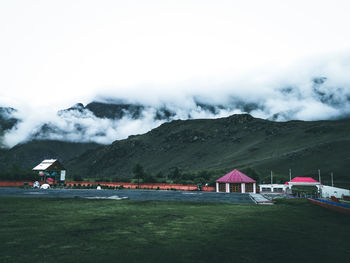 Scenic view of field by buildings against sky