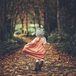 Rear view of girl walking in forest during autumn