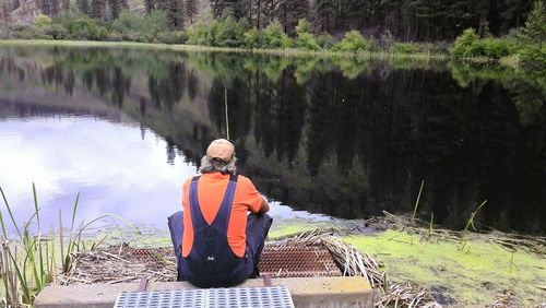 Rear view of man fishing at lakeshore