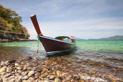 Boat moored on beach against sky