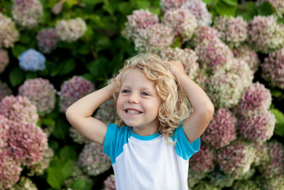 Smiling girl standing against pink flowering plants