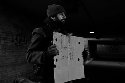 Homeless man holding banner with text