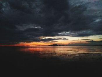 Scenic view of sea against dramatic sky during sunset