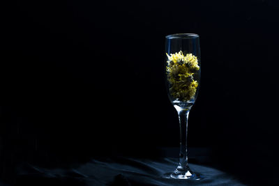 Wine glass on a black background there are yellow dried flowers in the wine glass