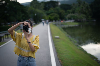 Series photo of young women wearing surgical protection mask playing with camera in the evening