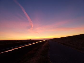 Road amidst land against sky during sunset