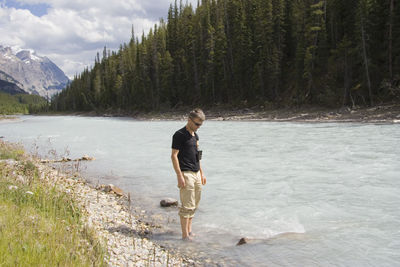 Side view of young man standing in river at banff national park