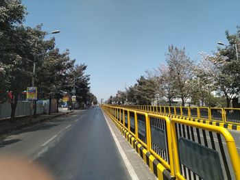 Road by trees against sky in city