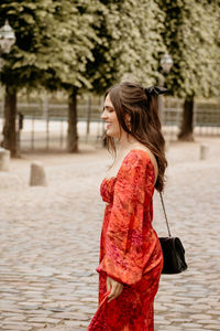 Happy woman with purse standing in park