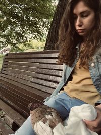 Young woman looking down while sitting on bench