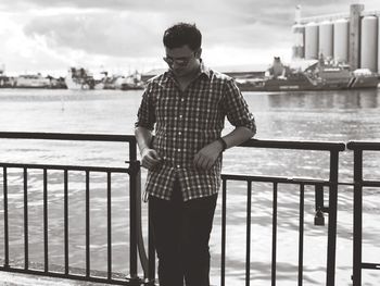 Young man standing by river in city