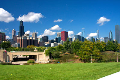 Trees and buildings in city against sky