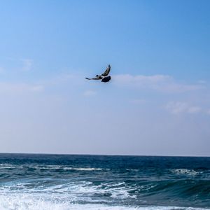 Helicopter flying over sea against sky