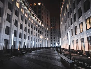 Illuminated street amidst buildings in city at night