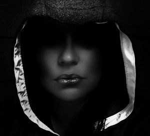 Close-up of woman wearing hood against black background