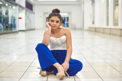 Portrait of young woman sitting on tiled floor