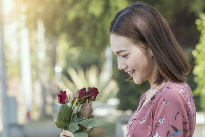 Close-up of smiling woman looking at red roses