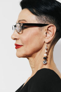 Close-up of young woman wearing sunglasses against white background