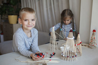 Cute sibling playing with christmas ornaments at home