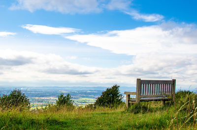 A wooden bench on the cotswold way overlooking cheltenham in gloucestershire in the english summer.