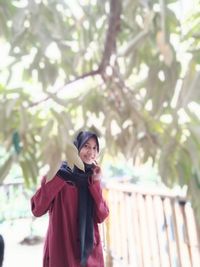 Woman standing by tree against plants in winter