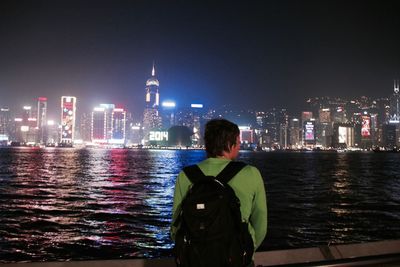 Rear view of man standing in city at night