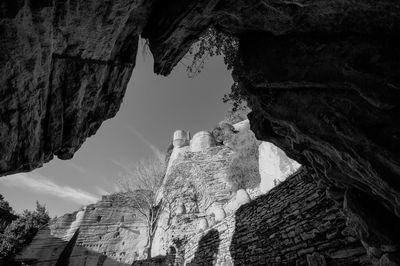 Low angle view of rock formation amidst buildings against sky