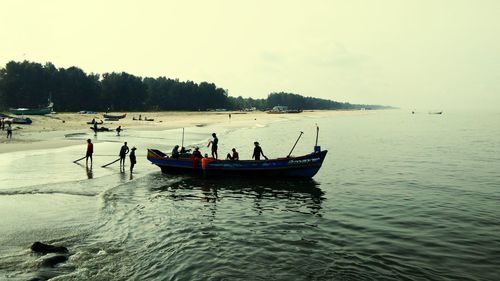 People on boat in sea against sky