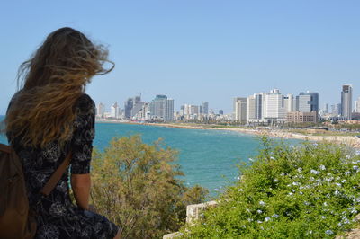 Rear view of woman standing by sea against clear sky