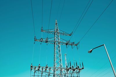 Low angle view of electricity pylon against clear blue sky