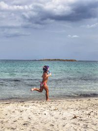 Full length of woman on beach against sky