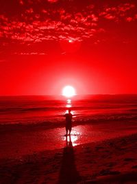 Silhouette man standing on beach against sky during sunset