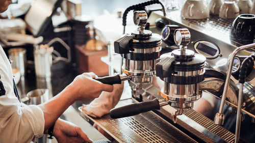 Midsection of woman making coffee at restaurant