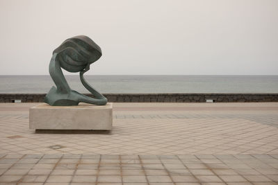 Statue by sea against clear sky