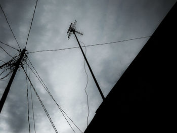 Low angle view of silhouette electricity pylon against sky