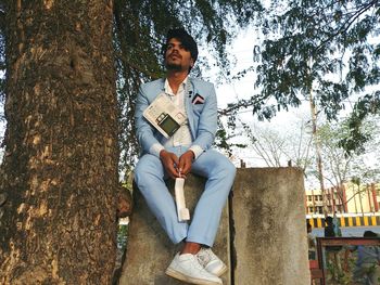 Young man sitting on tree trunk