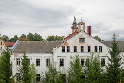 Exterior of old building by trees against sky