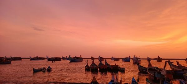 People at beach against sky during sunset