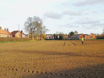 Houses on field by buildings against sky