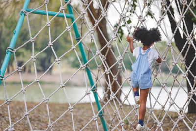 Rear view of girl standing by chainlink fence